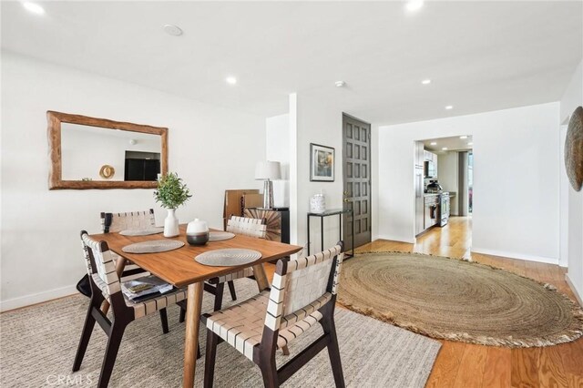 dining room with light wood-type flooring, recessed lighting, and baseboards