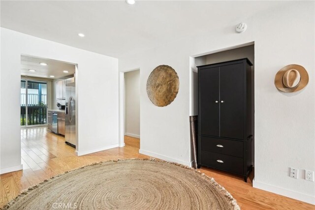 interior space with stainless steel fridge, baseboards, and light wood finished floors