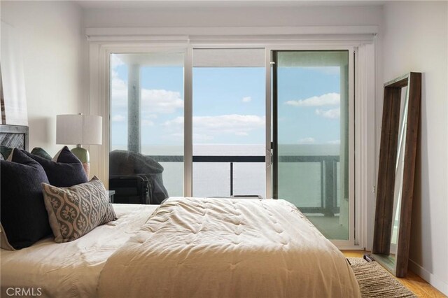 bedroom featuring baseboards, light wood finished floors, multiple windows, and access to exterior