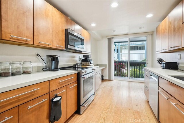 kitchen featuring light wood-style floors, appliances with stainless steel finishes, brown cabinets, and light countertops