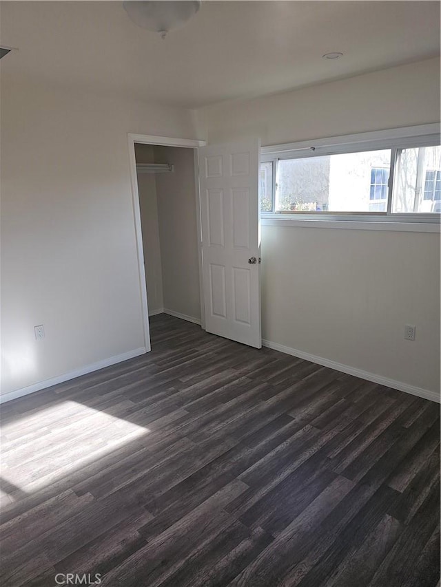 44645 Fig Ave, Lancaster, CA 93534 - unfurnished bedroom with baseboards, dark wood-style floors, and multiple windows