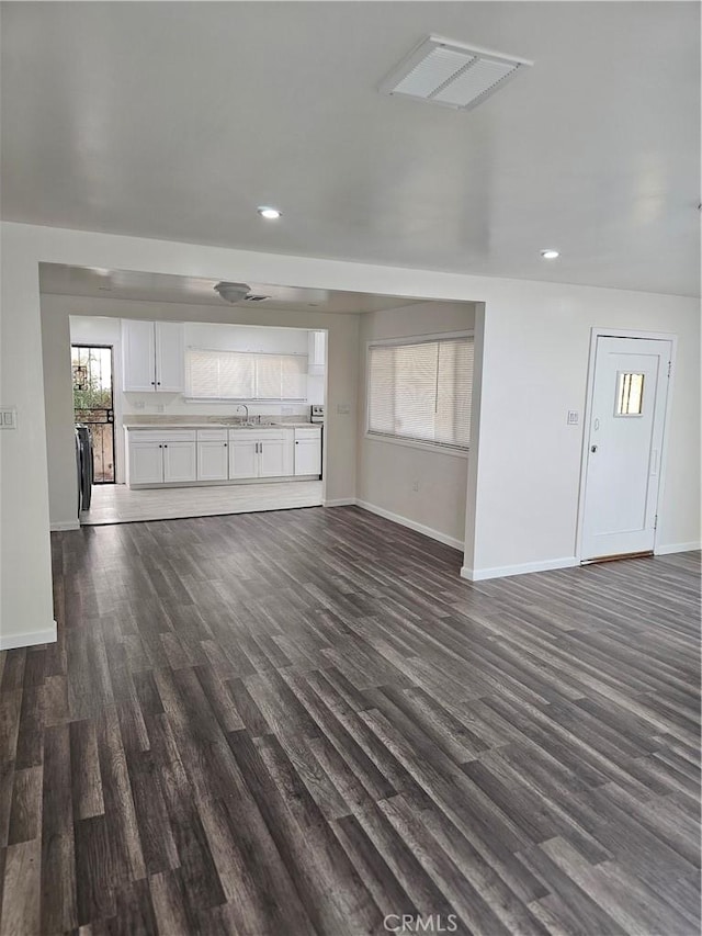 44645 Fig Ave, Lancaster, CA 93534 - unfurnished living room featuring visible vents, dark wood finished floors, a sink, baseboards, and recessed lighting
