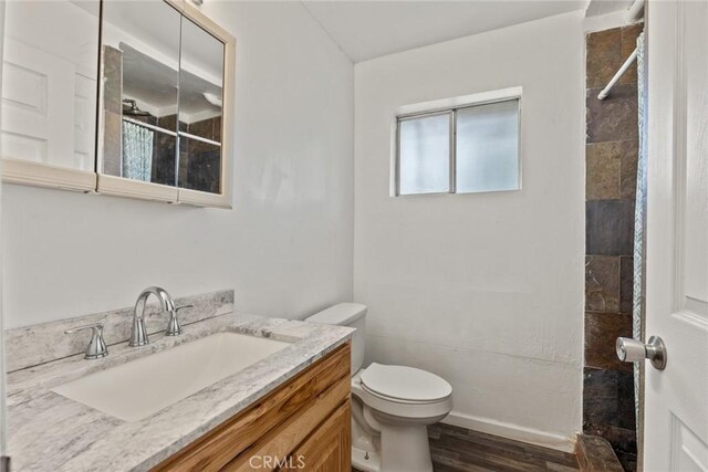 full bath featuring a shower with shower curtain, toilet, wood finished floors, and vanity