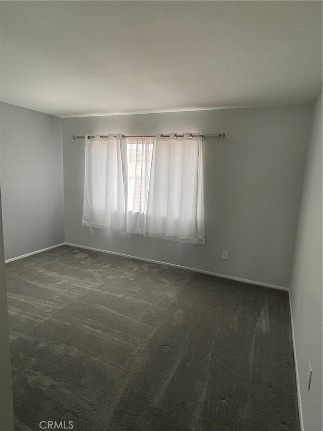 empty room with baseboards and carpet