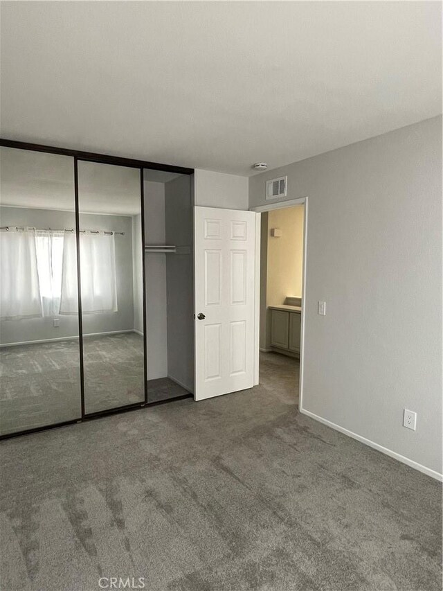 unfurnished bedroom with visible vents, carpet flooring, baseboards, and a closet