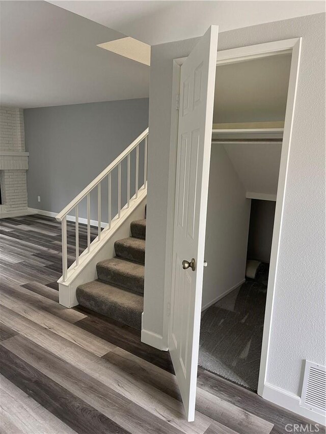 staircase featuring visible vents, baseboards, wood finished floors, and a fireplace