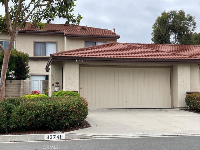 view of front of home featuring a tiled roof, an attached garage, driveway, and stucco siding