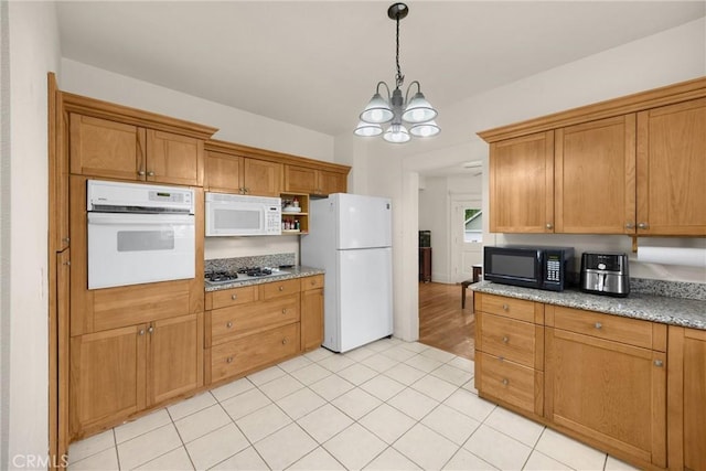 kitchen featuring pendant lighting, light stone countertops, brown cabinets, a chandelier, and white appliances