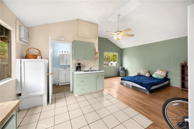 bedroom featuring a ceiling fan, a sink, light wood finished floors, connected bathroom, and lofted ceiling