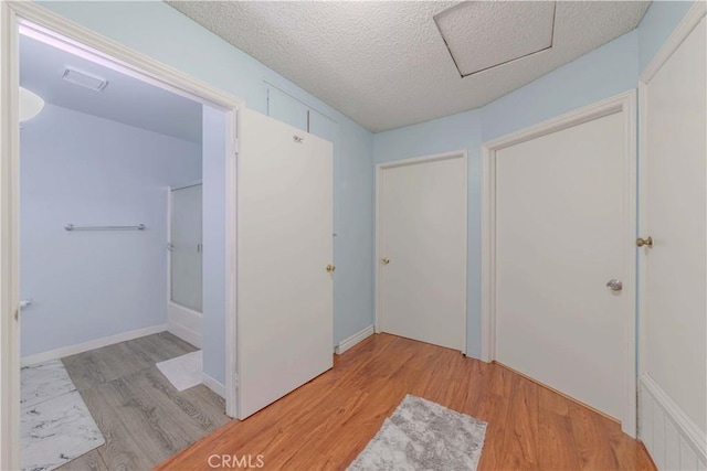 interior space with light wood finished floors, attic access, a textured ceiling, and visible vents