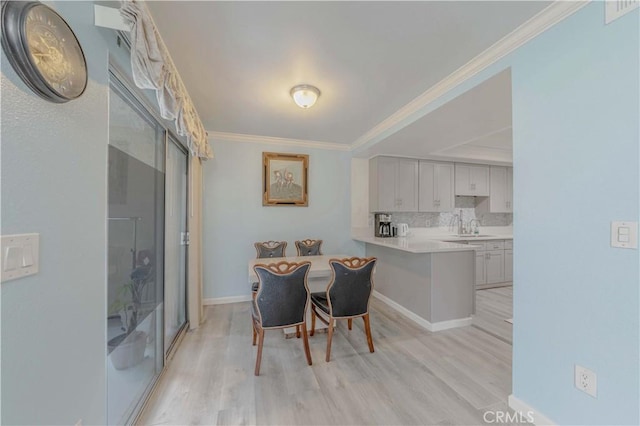 dining area with ornamental molding, light wood-style flooring, baseboards, and visible vents