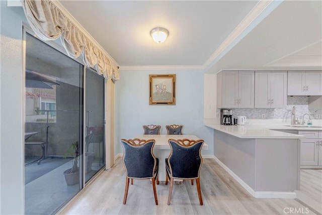 dining area with ornamental molding and light wood-type flooring