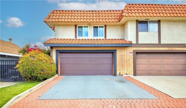 view of front of property featuring an attached garage, driveway, fence, and a tile roof