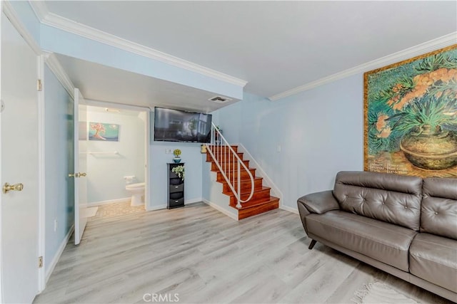 living room with ornamental molding, stairway, visible vents, and light wood-style floors