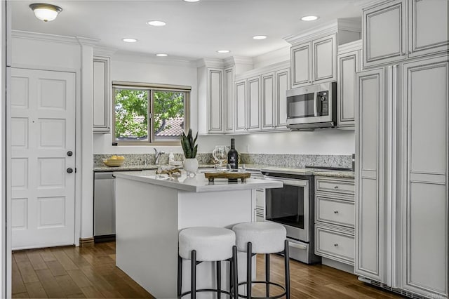 kitchen featuring light countertops, stainless steel appliances, dark wood-style floors, and a kitchen breakfast bar