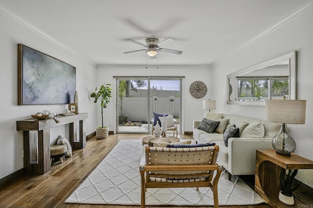 living area with baseboards, ornamental molding, a ceiling fan, and wood finished floors