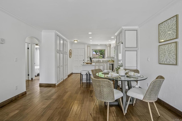 dining space featuring crown molding, baseboards, recessed lighting, arched walkways, and dark wood finished floors