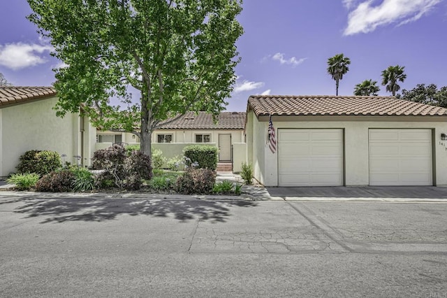 mediterranean / spanish house featuring a tiled roof, an attached garage, and stucco siding