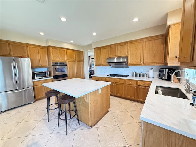 12271 Oldenberg Ct, Rancho Cucamonga, CA 91739 - kitchen featuring appliances with stainless steel finishes, a sink, under cabinet range hood, a kitchen island, and brown cabinets
