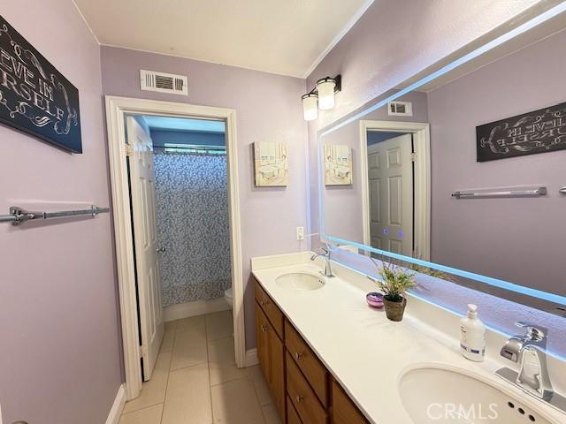 12271 Oldenberg Ct, Rancho Cucamonga, CA 91739 - bathroom with toilet, tile patterned flooring, double vanity, baseboards, and a shower with curtain