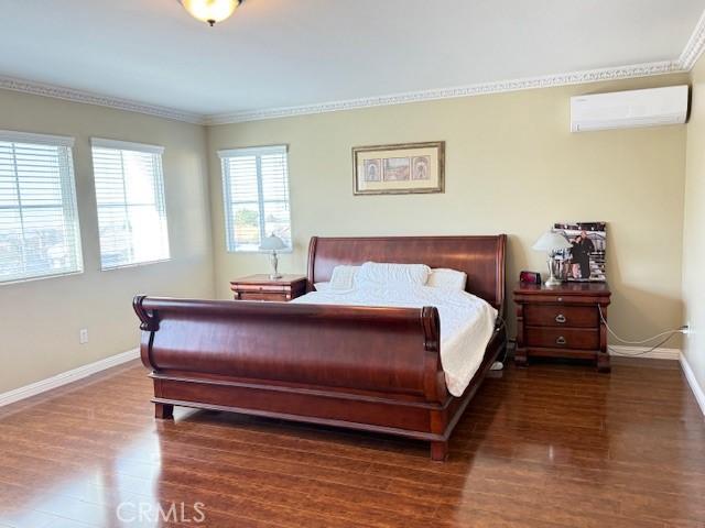 12271 Oldenberg Ct, Rancho Cucamonga, CA 91739 - bedroom with a wall mounted air conditioner, baseboards, wood finished floors, and ornamental molding