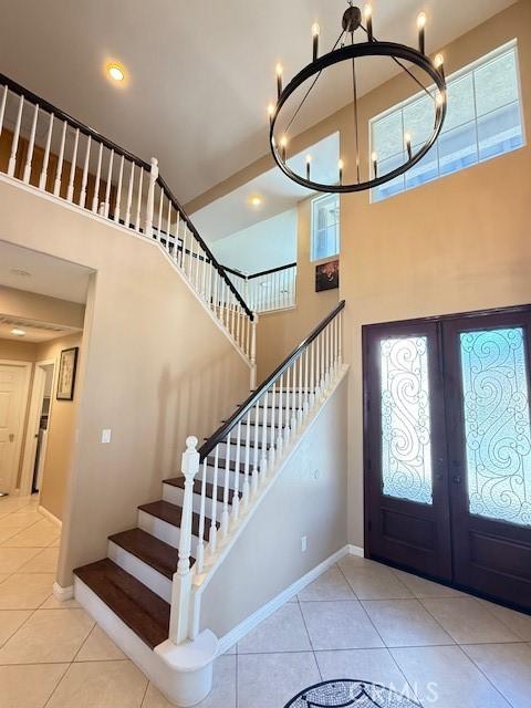 12271 Oldenberg Ct, Rancho Cucamonga, CA 91739 - foyer entrance with french doors, a high ceiling, a chandelier, tile patterned flooring, and stairway