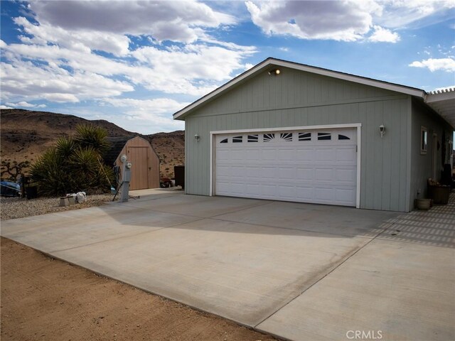view of side of home with an outdoor structure, a storage shed, and driveway
