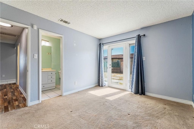 unfurnished bedroom featuring access to outside, carpet floors, a textured ceiling, baseboards, and visible vents
