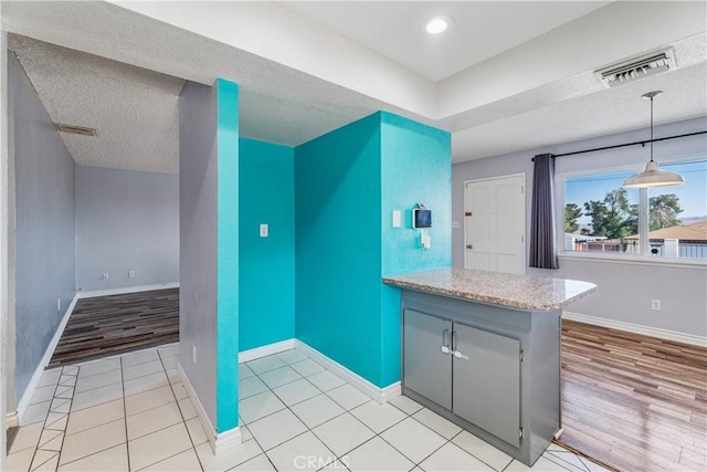 kitchen with visible vents, pendant lighting, baseboards, and light wood finished floors