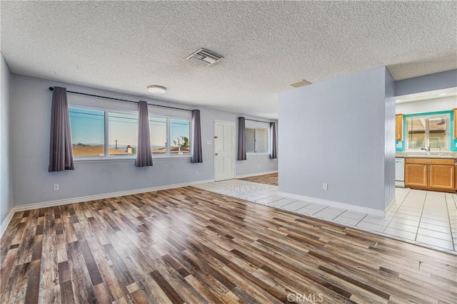 unfurnished room featuring a textured ceiling and light wood-style floors
