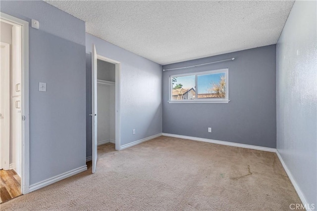 unfurnished bedroom with a closet, a textured ceiling, carpet, and baseboards