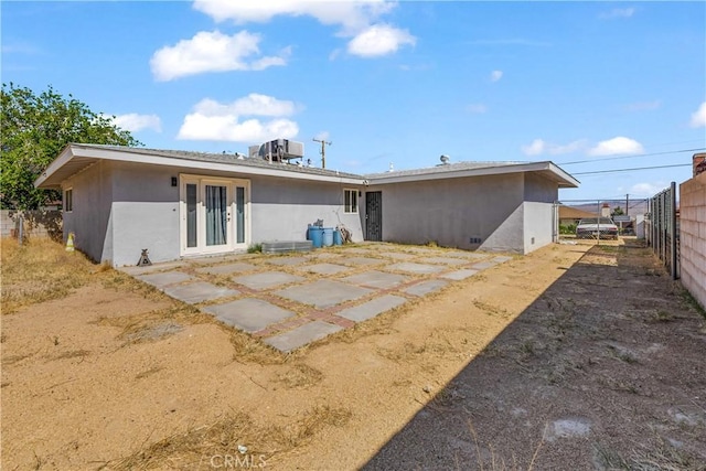 back of house with stucco siding, french doors, and fence