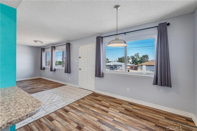interior space with baseboards, a textured ceiling, and wood finished floors