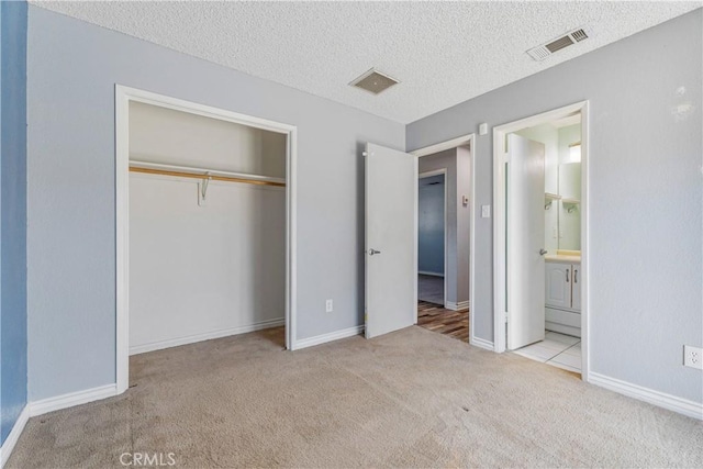 unfurnished bedroom with carpet floors, a closet, a textured ceiling, and visible vents