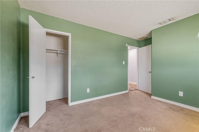 unfurnished bedroom featuring a closet, a textured ceiling, carpet, and visible vents