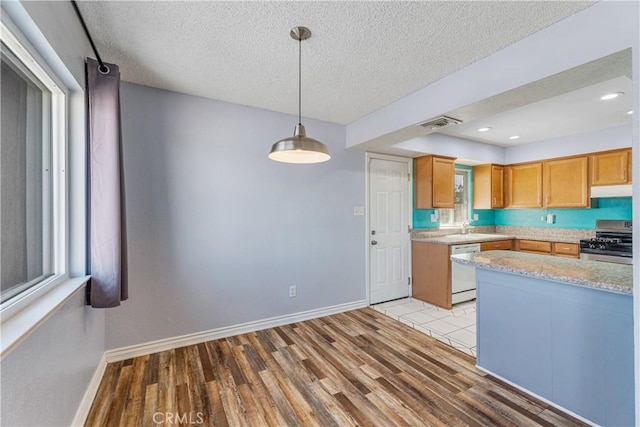 kitchen with stainless steel gas range oven, dishwasher, baseboards, light wood-type flooring, and under cabinet range hood