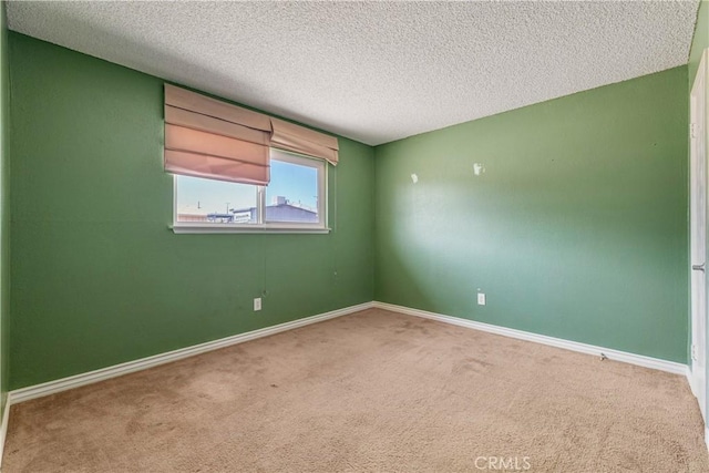 carpeted spare room featuring a textured ceiling and baseboards