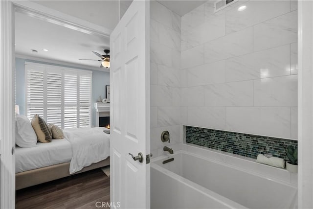 ensuite bathroom featuring ceiling fan, a washtub, visible vents, wood finished floors, and ensuite bathroom
