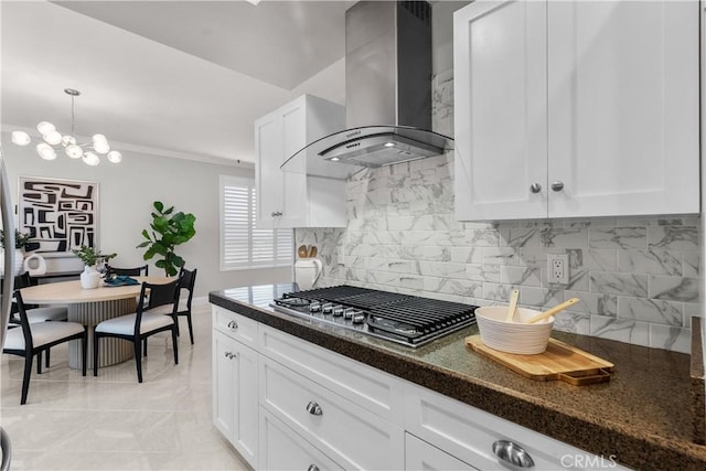 kitchen featuring decorative backsplash, wall chimney exhaust hood, stainless steel gas cooktop, and white cabinets