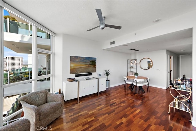 living area with baseboards, ceiling fan, wood finished floors, and visible vents