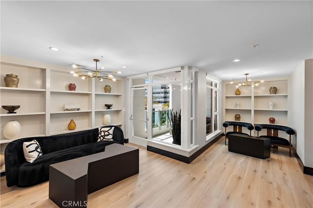 living area featuring recessed lighting, a notable chandelier, built in shelves, and light wood finished floors