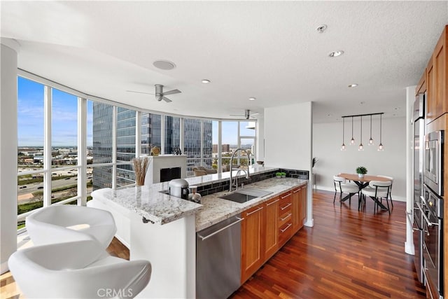 kitchen with a sink, brown cabinets, stainless steel appliances, and dark wood-style flooring