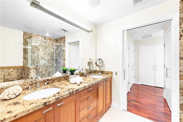 full bathroom featuring a sink, a shower stall, double vanity, and visible vents