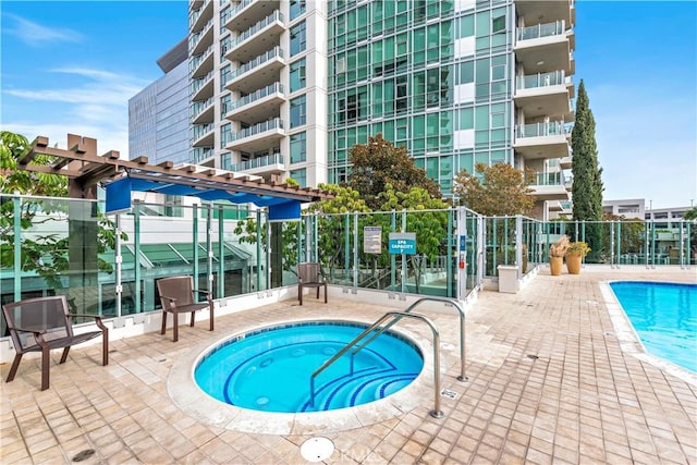 pool with fence, a community hot tub, and a patio area