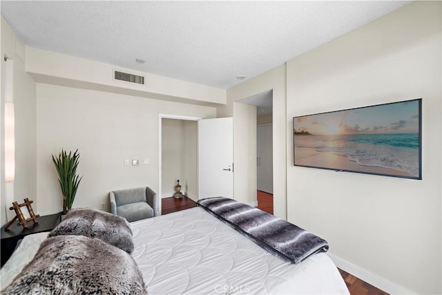 bedroom featuring baseboards, wood finished floors, and visible vents