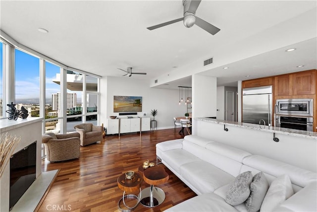 living area featuring visible vents, wood finished floors, a wall of windows, ceiling fan, and recessed lighting