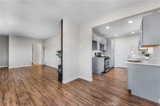 kitchen with stainless steel gas stove, baseboards, recessed lighting, gray cabinets, and dark wood finished floors