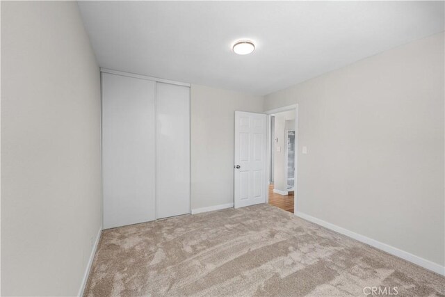 unfurnished bedroom featuring baseboards, carpet, and a closet