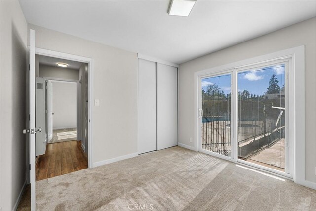 unfurnished bedroom with baseboards, carpet, a closet, and access to exterior