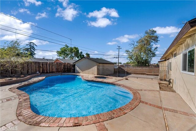 view of pool with a storage shed, a fenced backyard, a fenced in pool, an outbuilding, and a patio